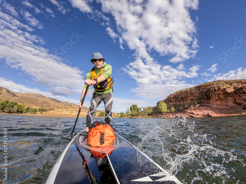 senior man paddling a stand up paddleboard photo