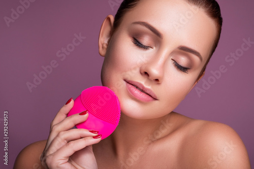 Beautiful brunette woman massage her face with a beauty massager. Her skin fresh, clean and flawless. Spa procedure concept