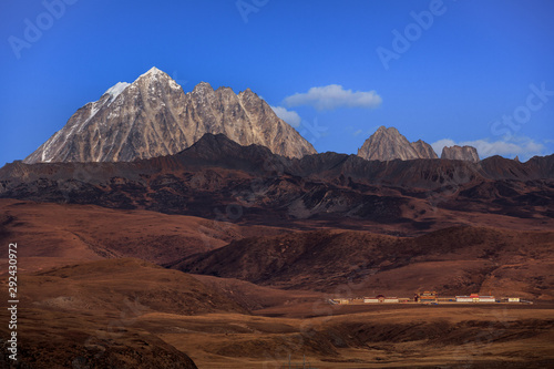 Tagong Prairie Grassland, Lhagang Grassland, Tibetan area of Sichuan Province China. Buddhist Monastery in foreground, Yala Snow Mountain towering in the distance. Strange Martian Landscape