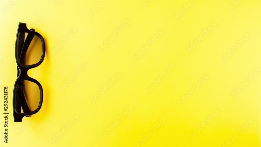 Stop motion animation of view from above of five pairs 3D black glasses of points line up and then disappear and only one pair of points remains on yellow background 