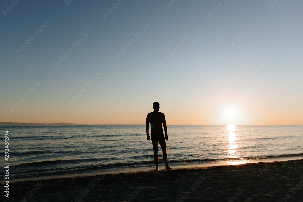 Young man looking at sunset by the sea