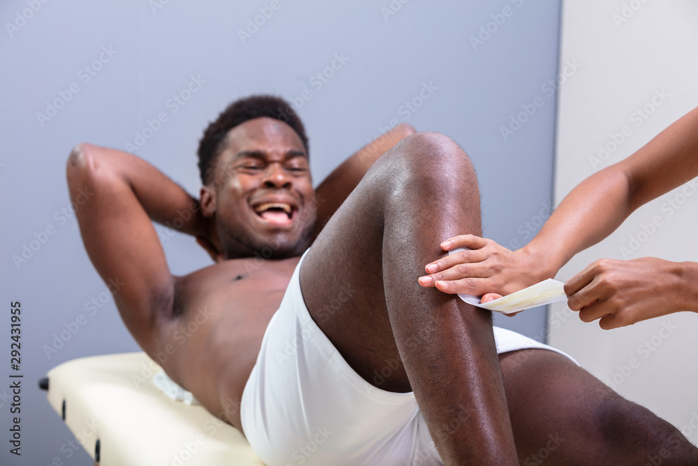 Therapist Waxing Man's Leg With Wax Strip Therapist Waxing Man's Leg With Wax Strip