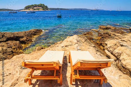 Fotografi Coastal summer landscape - view of the beach loungers on a rocky seashore, on th