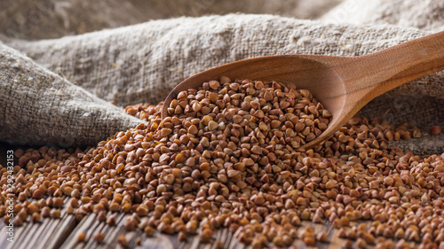 Rural still-life - the peeled groats of buckwheat (Fagopyrum esculentum) on the background of burlap, closeup with selective focus photo