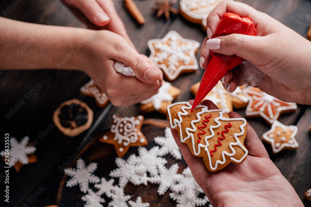 Christmas, New Year, DIY, holidays preparation and creativity concept. Getting ready to celebration. Friends decorating homemade gingerbread cookies with icing