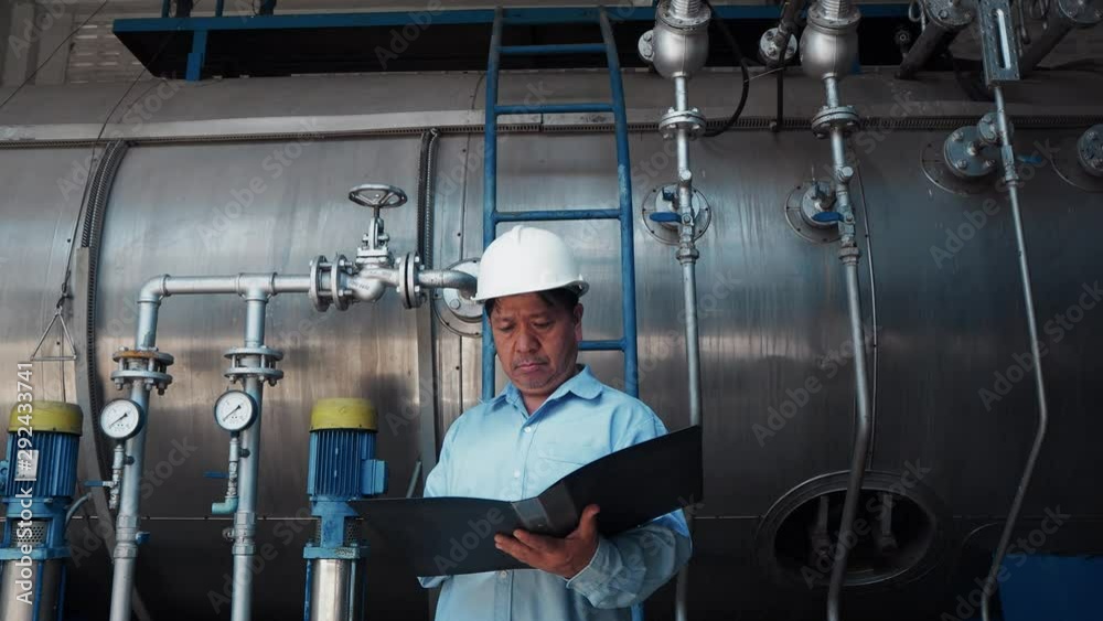 An asian senior engineer or mechanic reading manual in front of fuel power tank