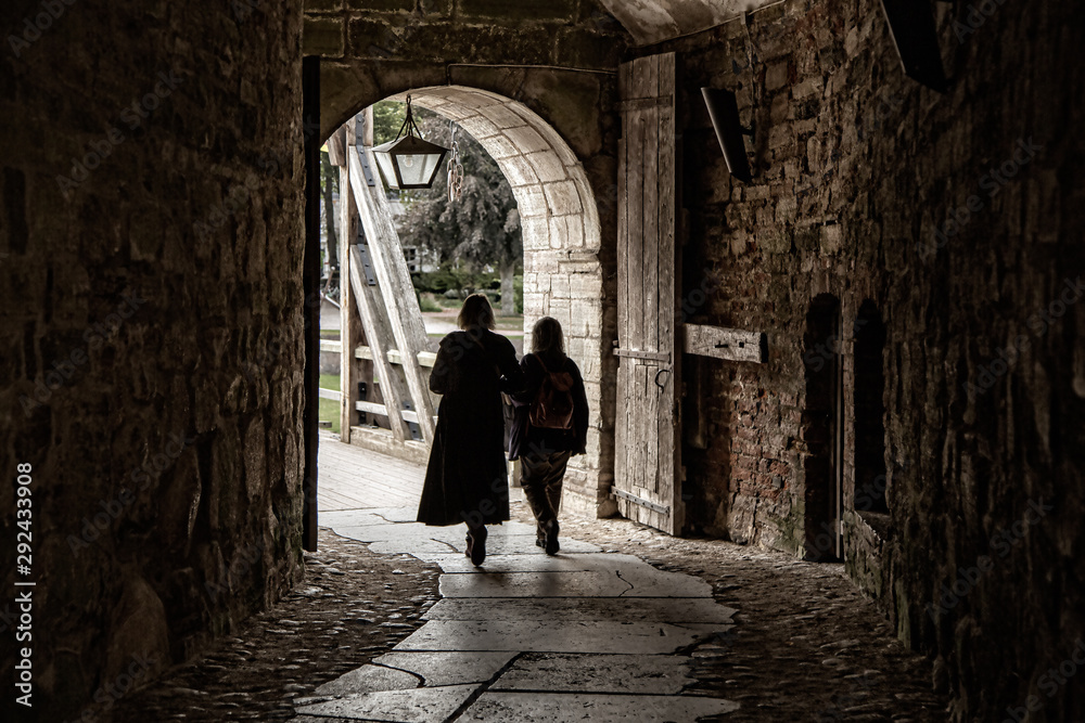 Two women walk through a castle arch