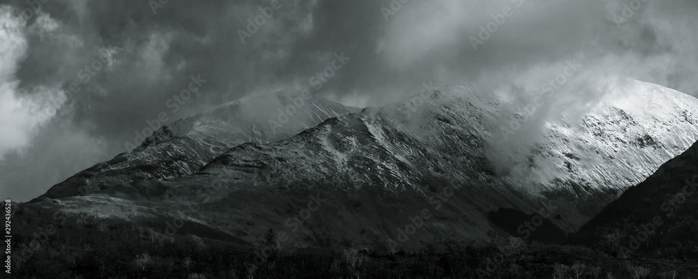 Black and White landscape. View towards Ballachulish across Loch Linnhe from Ardgour. Highlands of Scotland, with snow on the mountains and low hanging clouds with spots of sun breaking through. UK