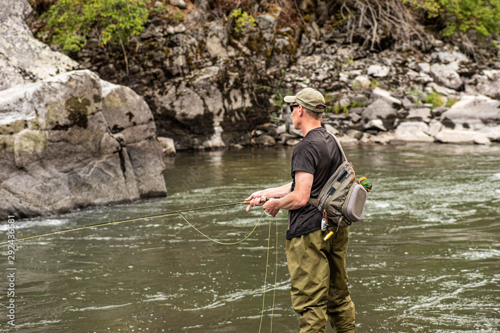 Fly fisherman casting in the mountain stream during the fall season. Fly fisherman casting in the mountain stream during the fall season.