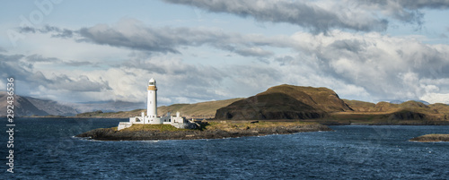 Eilean Musdile Lighthouse lit by the sun, in the West Coast of Scotland, seen from the ferry from Oban to Craignure, in the Isle of Mull. Seascape