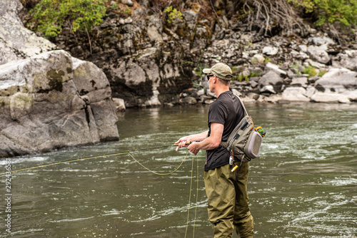 Fly fisherman casting in the mountain stream during the fall season.