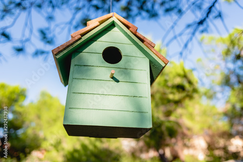 Wooden house for little birds hanging on a tree in a garden. © Joaquin Corbalan