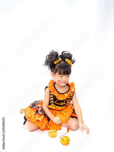 Asian children girl in pumpkin dress costume for Halloween decoration Holding a pumpkin in white background