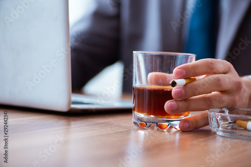 Male employee drinking alcohol and smoking cigarettes at workpla