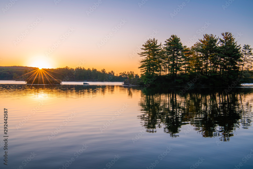 Obraz premium Peaceful sunrise over the lake at Harriman park, featuring sun raising over the mountains on the background