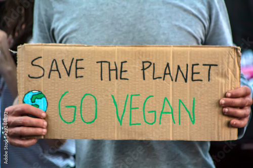 Activist with " Save the planet, Go Vegan" placard at climate change prostest