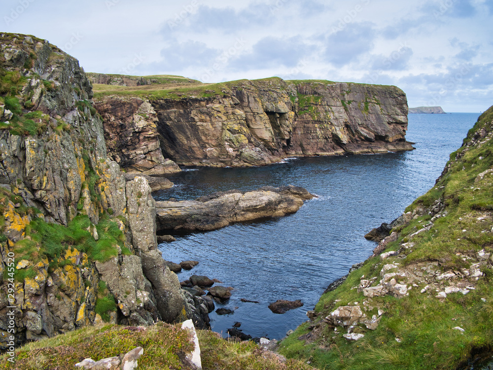 Sandstone cliffs on the East Shetland coast near Levenwick showing eroded rock strata - the bedrock is part of the Bressay Flagstone Formation, consisting of Sandstone and Argillaceous rocks, interbed Sandstone cliffs on the East Shetland coast near Levenwick showing eroded rock strata - the bedrock is part of the Bressay Flagstone Formation, consisting of Sandstone and Argillaceous rocks, interbed