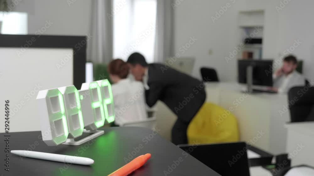 Clock in the foreground, people on the background in office. Clock in the foreground, people on the background in office.
