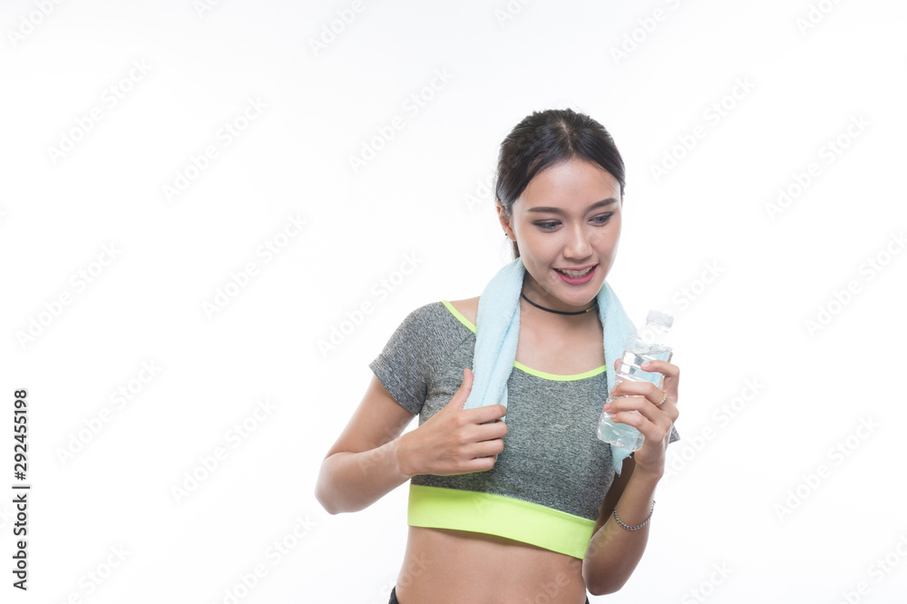 charming young girl in sports is smiling and hanging a towel and showing bottle of water, Healthy concept, Studio light portrait. charming young girl in sports is smiling and hanging a towel and showing bottle of water, Healthy concept, Studio light portrait.