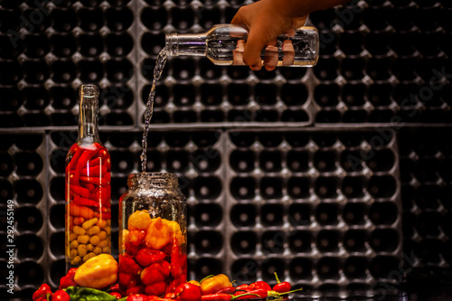 Peppers in motion ,colorful composition of peppers, chili sauce and preserved preserves in bottle and pot.
