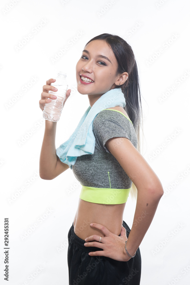 charming young girl in sports is smiling and hanging a towel and showing bottle of water, Healthy concept, Studio light portrait. charming young girl in sports is smiling and hanging a towel and showing bottle of water, Healthy concept, Studio light portrait.