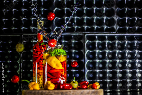 Peppers in motion ,colorful composition of peppers, chili sauce and preserved preserves in bottle and pot.