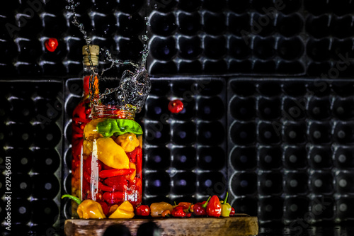 Peppers in motion ,colorful composition of peppers, chili sauce and preserved preserves in bottle and pot.