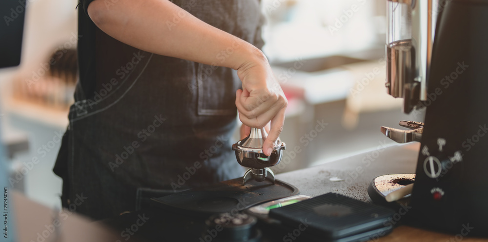 Close-up view of female barista hand's grinding coffee with grinder machine