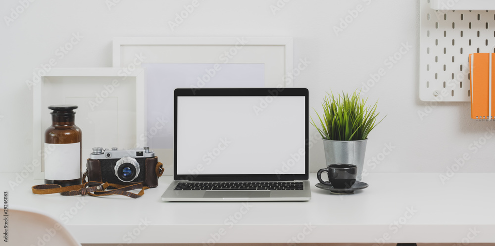 Trendy photographer workplace with blank screen laptop and office supplies