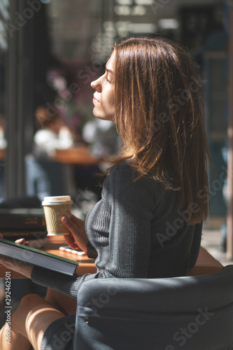 Caucasian girl student reads book in institute library and drinks coffee