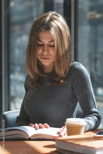 beautiful young girl schoolgirl reads book in school bookstore on sunny day