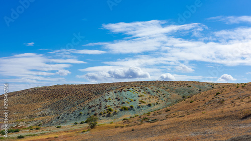 Clouds on a blue sky above a mountain with amazing green soil © Vastram