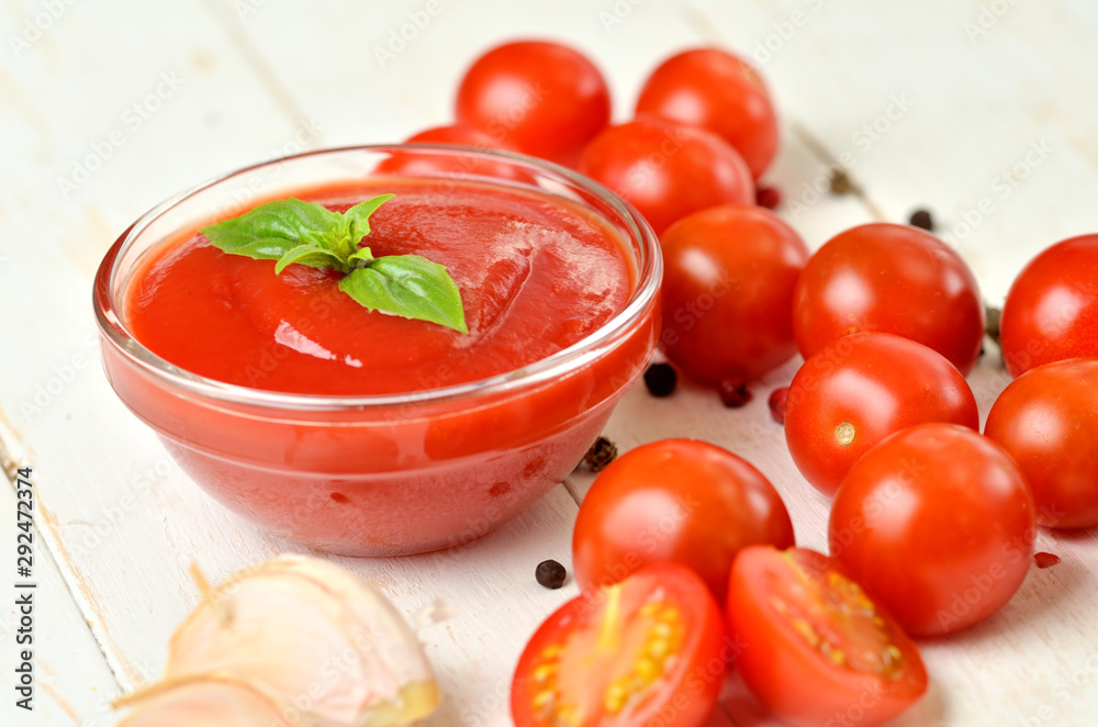 Close-up of bowl of homemade ketchup made from fresh tomatoes, garlic, basil on white rustic wooden background. Close-up of bowl of homemade ketchup made from fresh tomatoes, garlic, basil on white rustic wooden background.