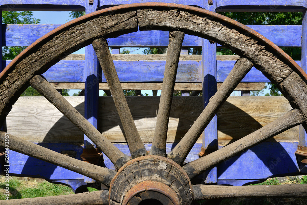 Demie roue en bois sur ancienne charette bleue