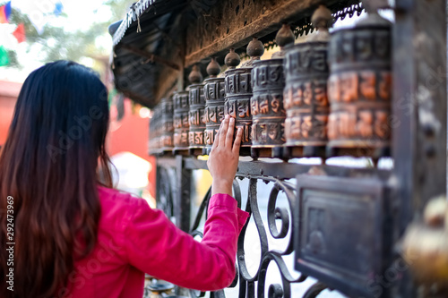 Bilde på lerret Young girl passing by Buddhist prayer wheel