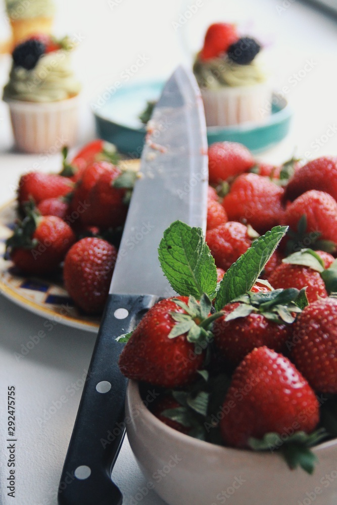 Fresh strawberries in a white bowl on a window