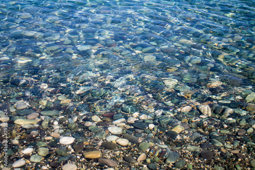 Sea stones in sea water. Pebbles under water. The view from the top. Nautical background. Clean sea water. Transparent sea.