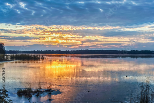 Colorful sunset on the lake covered with the first ice