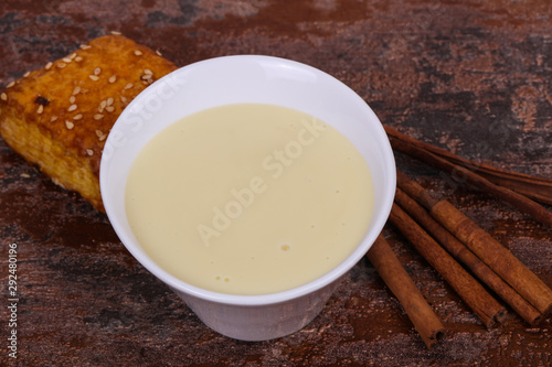 Condenced milk in the bowl with sinnamon and pastry photo