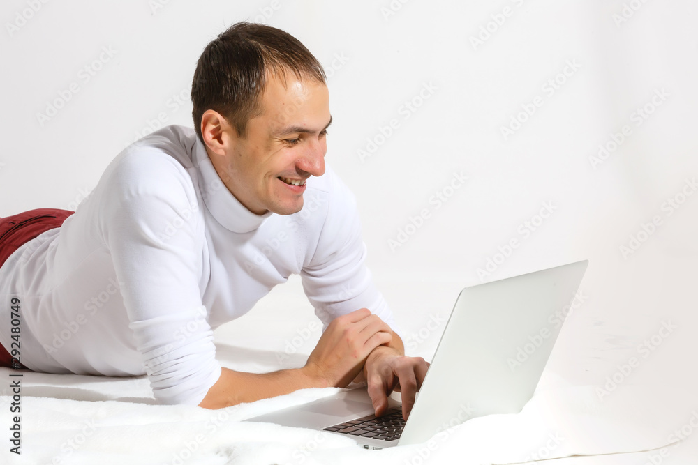 Surfing web at home. Cheerful young man lying on the floor with laptop, isolated over white background Surfing web at home. Cheerful young man lying on the floor with laptop, isolated over white background