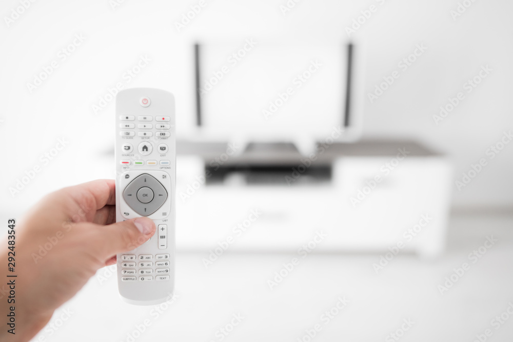Hand holding TV remote controller with a modern television set. Hand holding TV remote controller with a modern television set.