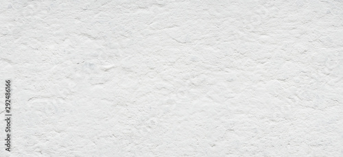 White background. Old rough concrete wall texture. Uneven cement surface covered by thin layer of white paint. Panorama. Closeup