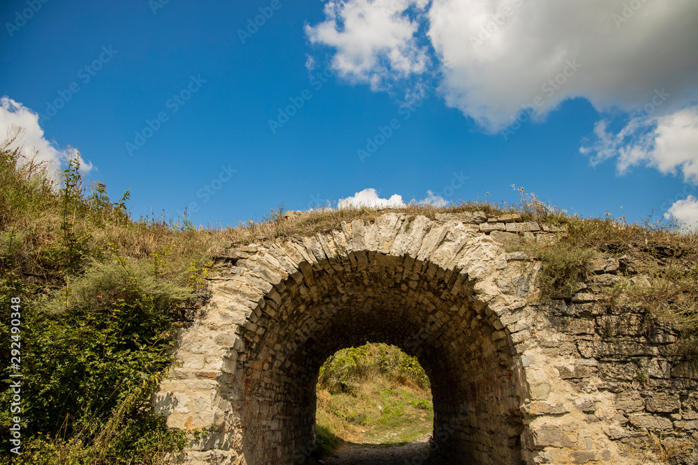 ancient stone arch tunnel building in Great Britain green hills country side outdoor space with blue sky white clouds background, copy space