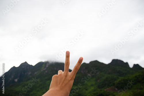 Two fingers in front of mountain view