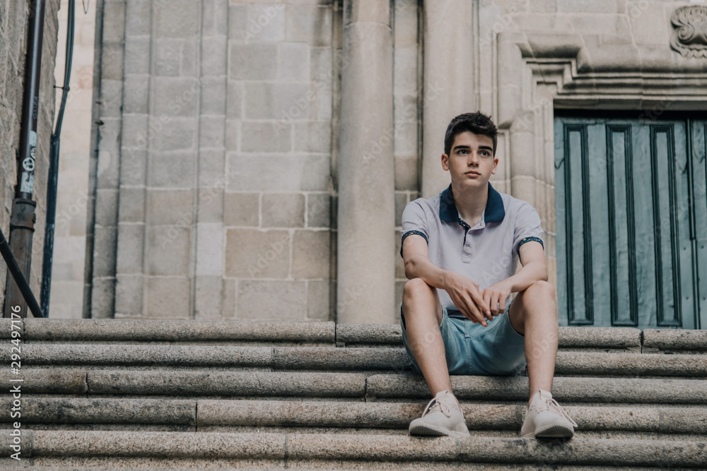 young teenage man with mobile phone in the city outdoors