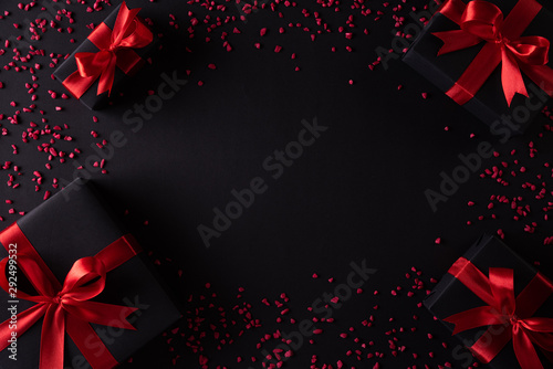 Top view of black christmas boxes with red ribbon on black background with copy space for text. black Friday composition.