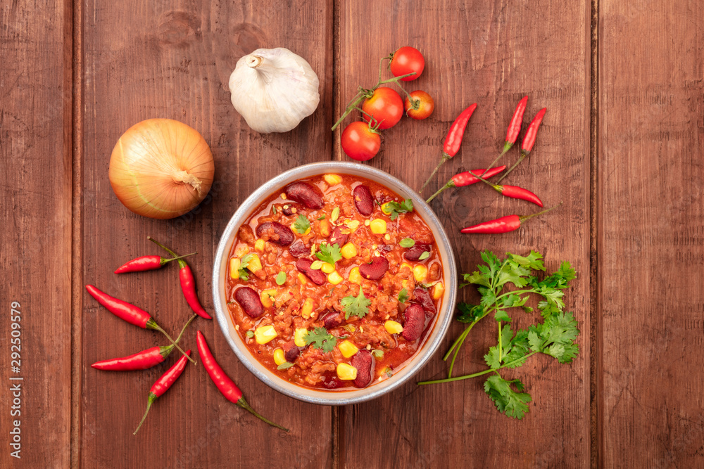 Chili con carne, shot from the top on a dark rustic wooden background with ingredients Chili con carne, shot from the top on a dark rustic wooden background with ingredients
