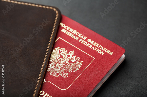 Brown leather cover with a red passport on a dark background