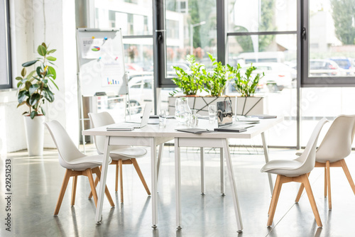 interior of office with table, chairs, green plants and digital devices