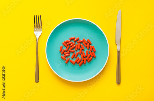 A many red capsules of antipyretic on a blue plate on yellow background with copy space. The concept of conventional medicine. Conceptually. Flat Lay. photo